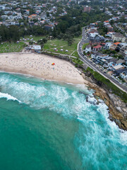 Aerial view of Bronte Beach in Sydney, Australia, with people enjoying the coastline, ocean pools and sandy shore, showcasing coastal lifestyle and summer atmosphere captured by drone