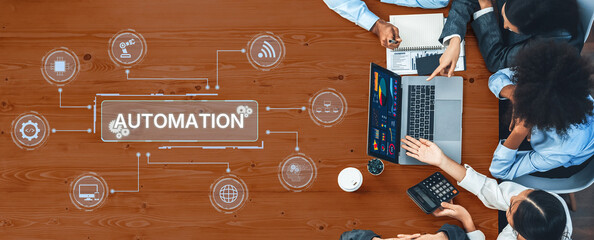 A diverse business team collaborates over a laptop in an engaging workspace, focusing on automation concepts and innovative approaches to enhance productivity. Trope