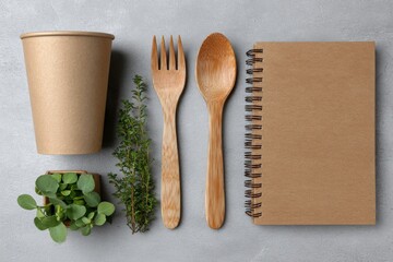 Eco friendly disposable tableware and notebook with fresh herbs on a textured background
