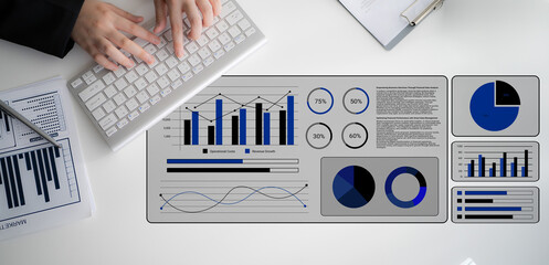 A modern business workspace showcasing hands typing on a keyboard with detailed graphs and charts...