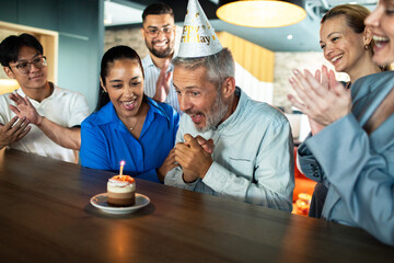 Mature man surprised by coworkers at office birthday celebration