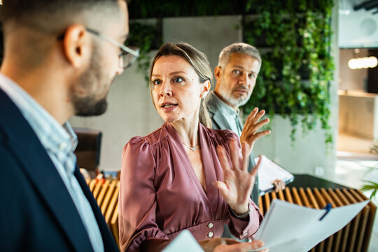 Adult and mature colleagues in tense discussion at modern office