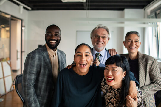 Adult and senior coworkers laughing together in modern office