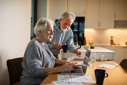 Senior couple concerned while paying bills at home kitchen