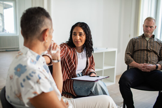Adult counselor comforting sad adult client in therapy room