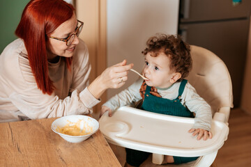 Mother Feeding Her Toddler with Love in the Kitchen