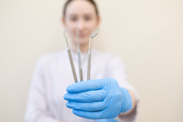 instruments in the hands of a dentist, with a dentist in the background in blur