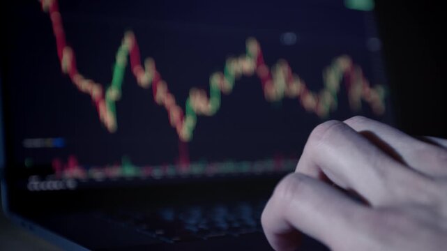 Cryptocurrency exchange on a laptop screen. Hand on keyboard. Close-up. Trading concept, financial markets, chart.
