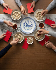 Overhead View of Family Sharing Dumplings and Red Envelopes for Lunar New Year