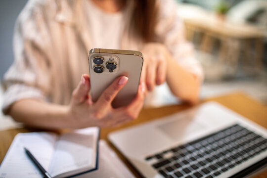 Young adult woman focused on smartphone at home office
