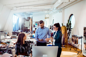 Adult coworkers discussing design ideas in fashion studio, focused and collaborative