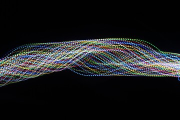 A long exposure photograph. Light painting photography, vibrant multicolour fairy lights against a black background