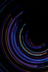 A long exposure photograph. Light painting photography; vibrant multicolour fairy lights in a circle swirl pattern against a black background