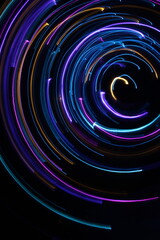 A long exposure photograph. Light painting photography; vibrant multicolour fairy lights in a circle swirl pattern against a black background