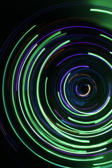 A long exposure photograph. Light painting photography; vibrant multicolour fairy lights in a circle swirl pattern against a black background