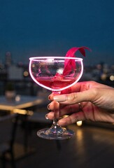 Hand Holding a Glowing Neon Cocktail on a Rooftop Bar at Night