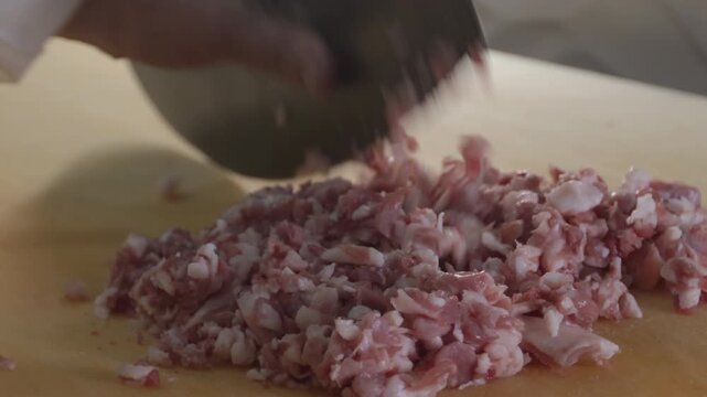 Artisanal hand-mincing of meat using a traditional satir cleaver for Gaziantep style onion kebab. High-quality 10-bit slow motion highlighting professional meat preparation. 4K.