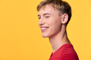 Smiling man in a red shirt against a bold yellow backdrop, conveying warmth, approachability and...