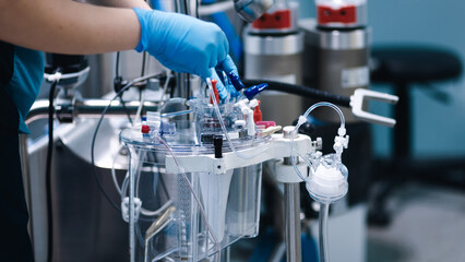 Medical professional in blue gloves operates advanced surgical equipment in a sterile operating room, showcasing precision and focus in a critical healthcare environment