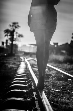 Woman walking on railway track balancing in high heels, concept of risk, uncertainly and life journey in black and white	