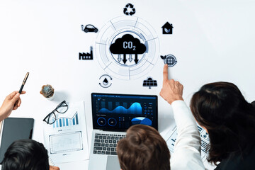 A collaborative team analyzing data on a laptop for carbon reduction strategies. Focus on technology integration and sustainable practices in business environments. Trope