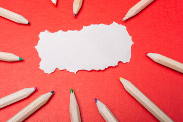 multi color wooden pencils and blank white torn paper