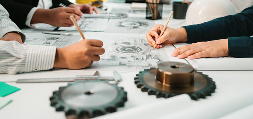 Engineers and designers engage in a collaborative session, creating technical drawings and schematics with various tools and gears in a modern office setting. SACTR
