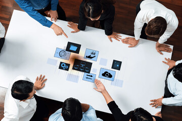 Diverse team engages in collaboration around digital interface on table, discussing project management and business strategies in modern office setting. Trope