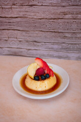 Imagen vertical de un plato de flan napolitano con frutos rojos postre perfecto