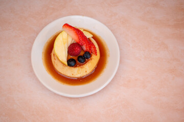 Imagen horizontal de un flan napolitano con caramelo derretido y frutos decorados arriba