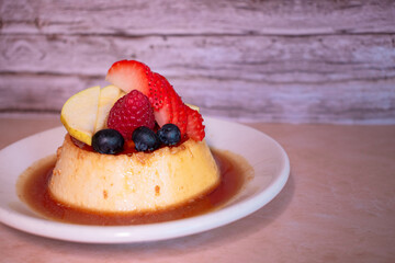 Plano horizontal a detalle de un flan napolitano con caramelo derretido y frutos rojos delicioso postre