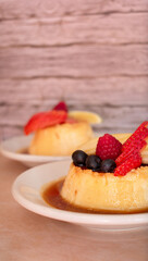 Imagen horizontal a detalle de un flan de leche con frutos rojos y caramelo