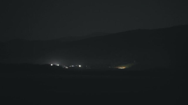 Driving at night along the misterious illuminated object in mountain with out-of focus nice bokeh lights, selective focus
