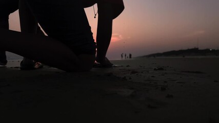 Calm evening moment of kids playing on sea beach during nightfall beneath a painted sky and glowing sky.