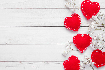 Valentines Day side border of cloth hearts and white flowers. Overhead view on a white wood background. Copy space.