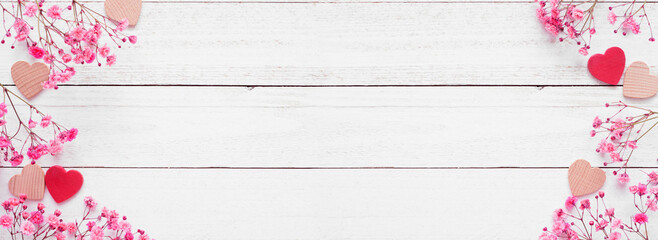 Valentines Day double border of wood hearts and pink flowers. Above view on a white wood banner background. Copy space.