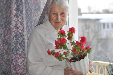 Old lonely woman sitting near the window