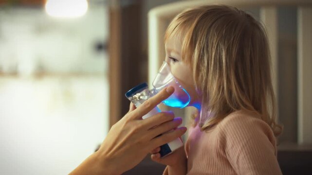 Mother's gentle hands assist her young daughter with nebulizer treatment, easing respiratory issues in bronchi helping loosen mucus, common symptom asthma bronchitis, thus providing soothing therapy
