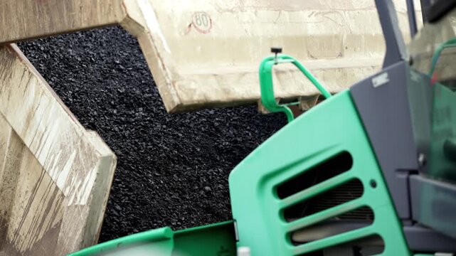Transport hot asphalt into bulldozer scoop to the spreader machine, slow motion