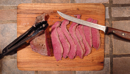 Slow cooked sliced corned beef on a wood cutting board