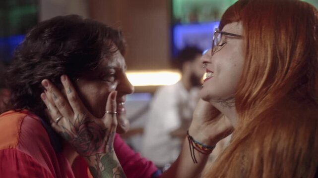 Romantic moment of a lesbian couple kissing in a dimly lit bar, celebrating love and diversity.