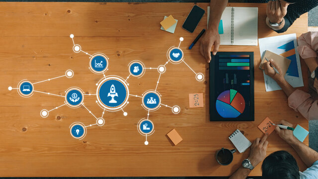 Collaborative Business Strategy Session with Graphs and Data Visualization on Wooden Table Featuring Icons for Innovation and Performance. Amity - Powered by Adobe