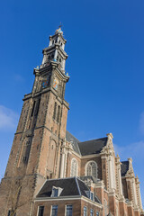 Low angle view of the famous Westerkerk tower in Amsterdam, Netherlands, featuring the iconic blue imperial crown under a clear blue sky.