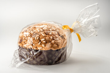 Panettone Christmas cake covered with sugar icing and almonds, packaged in a transparent plastic bag closed with gold ribbon.