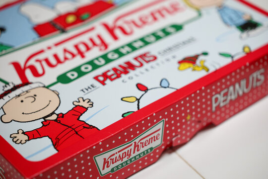 General view of a colorful box of Krispy Kreme doughnuts featuring Peanuts characters Charlie Brown, Snoopy, Woodstock and more for a Christmas holiday promotion. 