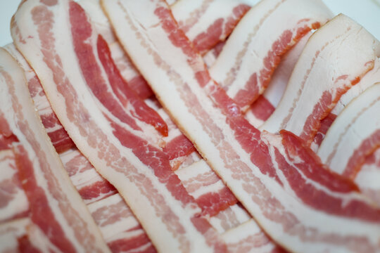 Raw bacon stacked in a criss cross pattern before getting cooked for breakfast. 