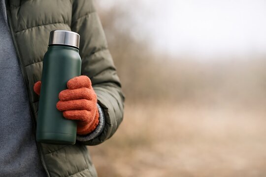 Green reusable thermos bottle in hand outdoor lifestyle