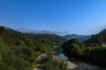Serene landscape with misty morning fog over green meadow and mountains
