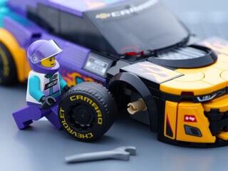 Obraz premium Tambov, Russian Federation - January 02, 2026 Lego driver minifigure changing wheel of his Lego NASCAR Next Gen Chevrolet Camaro ZL car. LEGO Speed Champions.