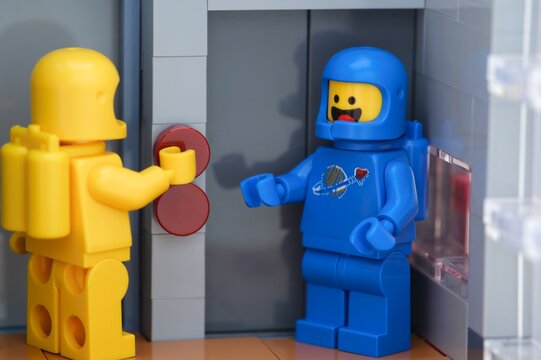 Tambov, Russian Federation - May 26, 2025 Close-up of two Lego astronaut minifigures waiting at an elevator. The yellow one is pressing a button on the elevator.